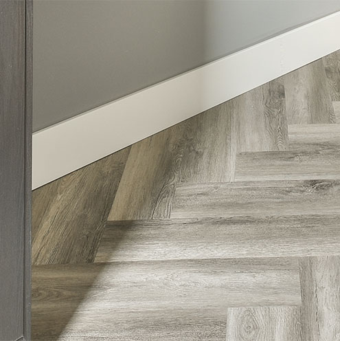 Luxury vinyl tile (LVT) fitted against a wall with skirting